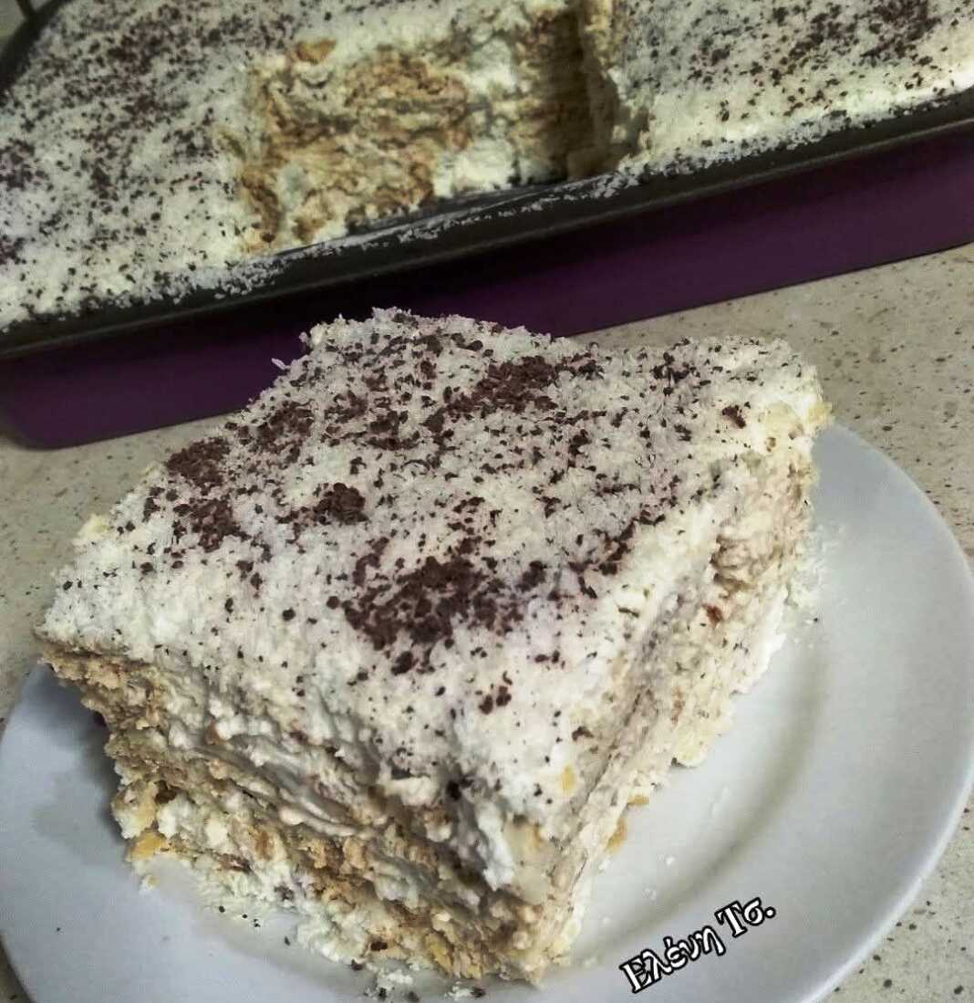 Ένα δροσερό γλυκό ταψιού καλυμμένο με πλούσιο λευκό ινδοκάρυδο και τριμμένη κουβερτούρα, κομμένο σε τετράγωνα κομμάτια