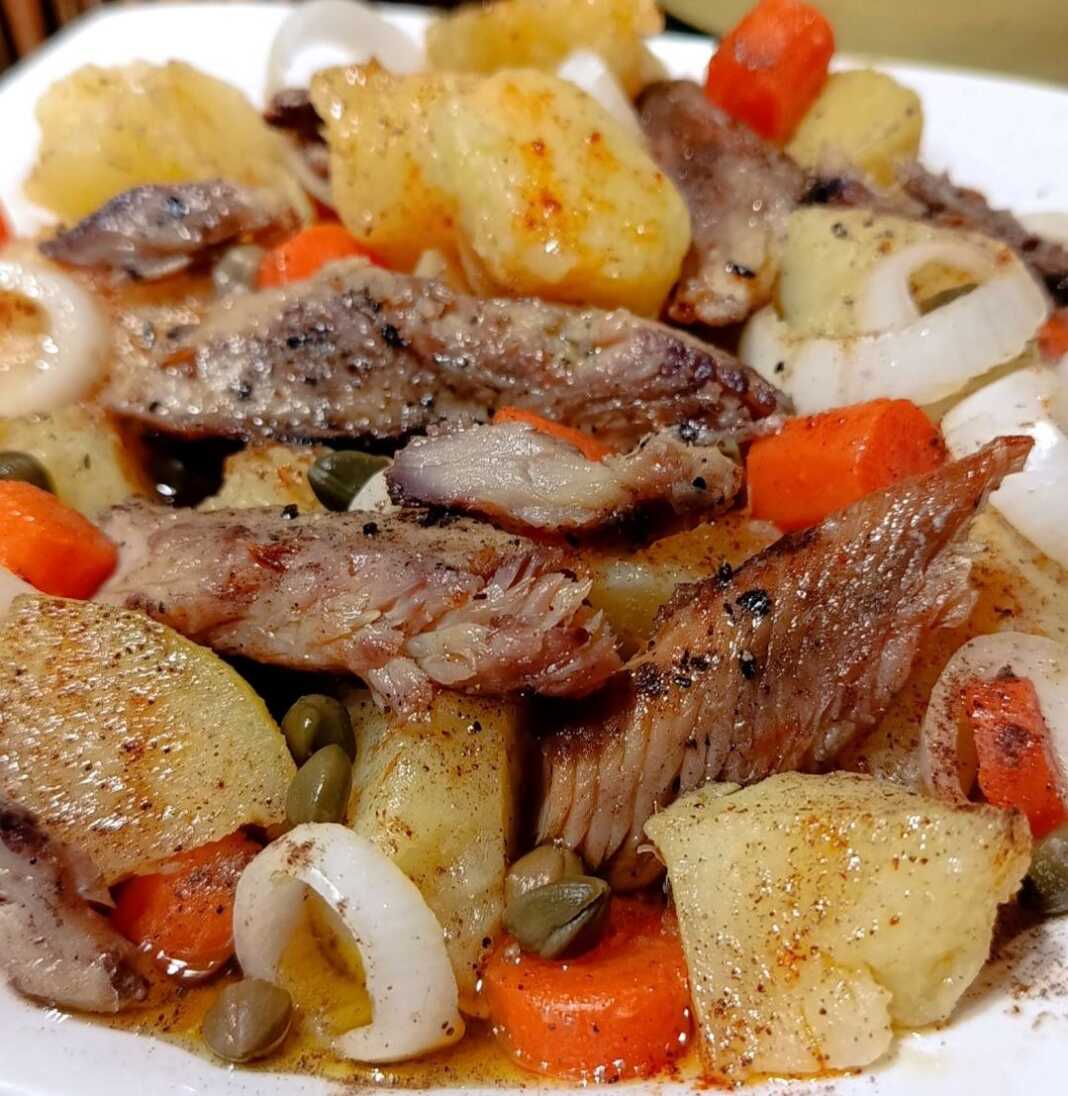 Ένα μεγάλο πιάτο με Ρεγγοσαλάτα, που περιέχει κομμάτια καπνιστής ρέγγας, ροδέλες πατάτας και καρότου, και κάππαρη, πασπαλισμένο με πάπρικα.