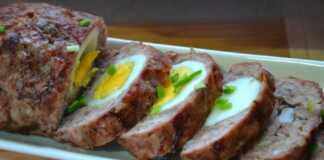 Ένα λαχταριστό ρολό κιμά κομμένο σε φέτες, με ένα ολόκληρο βραστό αυγό στο κέντρο, σερβιρισμένο σε πιατέλα.