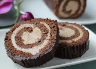 Ένα ρολό παντεσπάνι σοκολάτας τυλιγμένο, καλυμμένο με γυαλιστερό γλάσο σοκολάτας, με την κρέμα να φαίνεται στο εσωτερικό του ρολού.