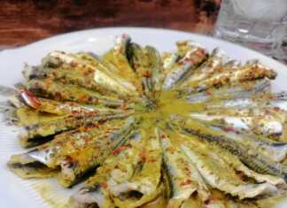 Καθαρισμένες σαρδέλες τοποθετημένες κυκλικά σε πιάτο, μαγειρεμένες με κίτρινη σάλτσα κουρκουμά και κόκκινο μπούκοβο.