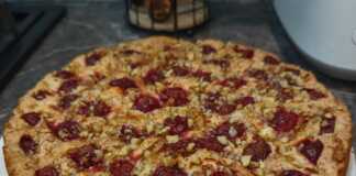 Ένα μεγάλο κομμάτι αφράτου κέικ Σαρλοτ με ροδοκοκκινισμένη κρούστα, γεμιστή με ολόκληρα κεράσια και φέτες μήλου,