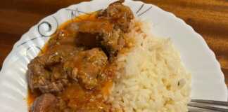 Μια κατσαρόλα με αχνιστό, κάτασπρο και σπυρωτό ρύζι, έτοιμο να σερβιριστεί ως συνοδευτικό.