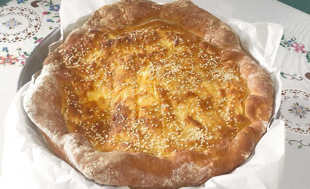 Ένα μεγάλο στρογγυλό τυρένιο ψωμάκι (σαν χατσαπούρι) πασπαλισμένο με σουσάμι, με χρυσαφί κρούστα και λιωμένη γέμιση τυριού.