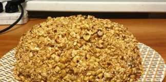 Κομμένη τούρτα με τρία επίπεδα παντεσπάνι και ενδιάμεσα πλούσια κρέμα Σαρλότ, καλυμμένη με κρέμα και ψιλοκομμένα φιστίκια.