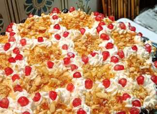 Τούρτα με Πλούσια Κρέμα Πατισερί και Καραμελωμένα Αμύγδαλα Μια επιβλητική τούρτα με ροζέτες σαντιγής, καλυμμένη με καραμελωμένα αμύγδαλα, σπόρους ροδιού και γλυκό κουταλιού αρώνια πάνω σε γιορτινή πιατέλα.