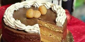 Μια εντυπωσιακή τούρτα μους κάστανο καλυμμένη με γυαλιστερό γλάσο σοκολάτας γάλακτος και γιορτινή διακόσμηση.