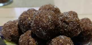 Στρογγυλά σκούρα καφέ τρουφάκια τυλιγμένα σε σκόνη κακάο και ψίχουλα μπισκότου, σερβιρισμένα σε πιατέλα.