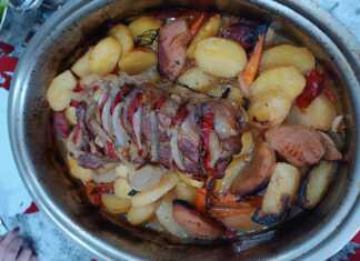 Ένα καλοψημένο χοιρινό ρολό τοποθετημένο πάνω σε μια πανδαισία λαχανικών με πατάτες, καρότα και κυδώνια μέσα σε πήλινη γάστρα.