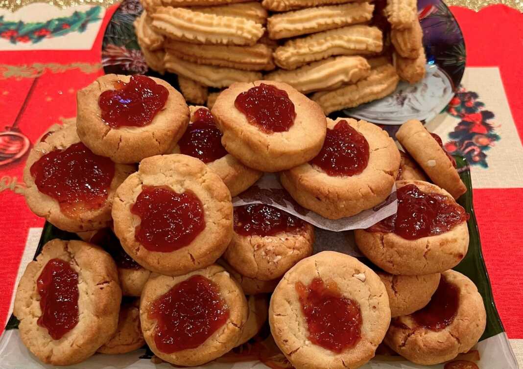 Δίσκος με στρογγυλά χριστουγεννιάτικα μπισκότα με αμύγδαλο και μια λακκούβα στη μέση γεμάτη με κατακόκκινη μαρμελάδα.