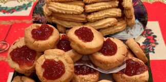 Δίσκος με στρογγυλά χριστουγεννιάτικα μπισκότα με αμύγδαλο και μια λακκούβα στη μέση γεμάτη με κατακόκκινη μαρμελάδα.