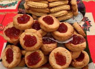 Δίσκος με στρογγυλά χριστουγεννιάτικα μπισκότα με αμύγδαλο και μια λακκούβα στη μέση γεμάτη με κατακόκκινη μαρμελάδα.