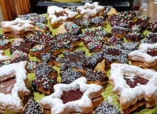 Διαφορετικά χριστουγεννιάτικα μπισκότα (αστέρια, δέντρα, κ.λπ.) γεμιστά με μαρμελάδα ή με γλάσο σοκολάτας, σερβιρισμένα σε γιορτινή πιατέλα.