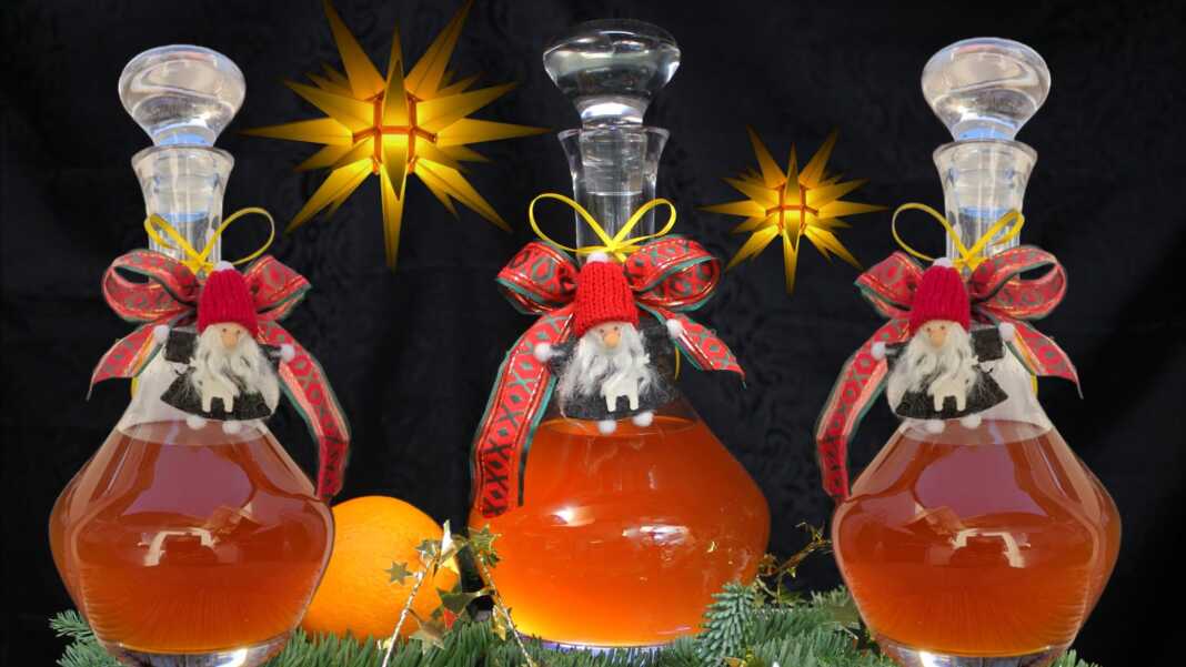 Χειροποίητο λικέρ πορτοκάλι με κορμούς κανέλας και γαρίφαλα μέσα σε μπουκάλι γυάλινο, με φόντο χριστουγεννιάτικης διακόσμησης.