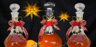 Χειροποίητο λικέρ πορτοκάλι με κορμούς κανέλας και γαρίφαλα μέσα σε μπουκάλι γυάλινο, με φόντο χριστουγεννιάτικης διακόσμησης.