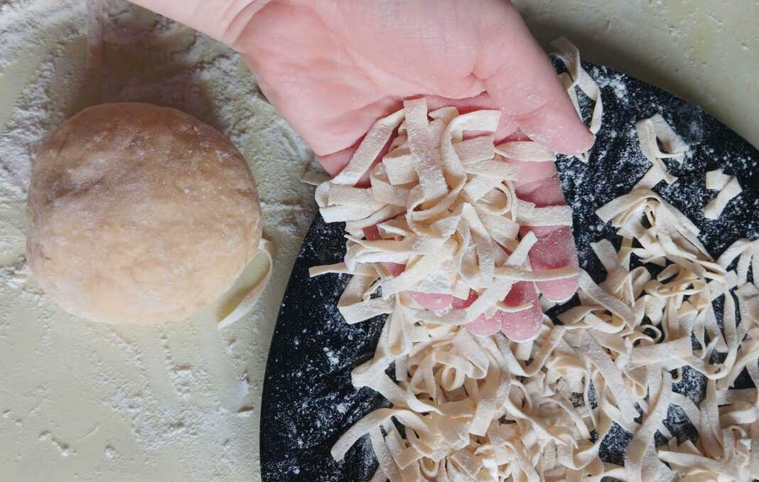 Φωτογραφία με χρυσαφένια σπιτικά ζυμαρικά (π.χ. ταλιατέλες) , έτοιμα για βράσιμο.