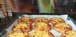 Αφράτα Σπιτικά Πιτσάκια: Το Τέλειο Κολλατσιό για Μικρούς και Μεγάλους! Ένας δίσκος με εννέα χρυσαφένια και αφράτα σπιτικά πιτσάκια, γεμάτα με λουκάνικο, λιωμένο τυρί και μυρωδικά.