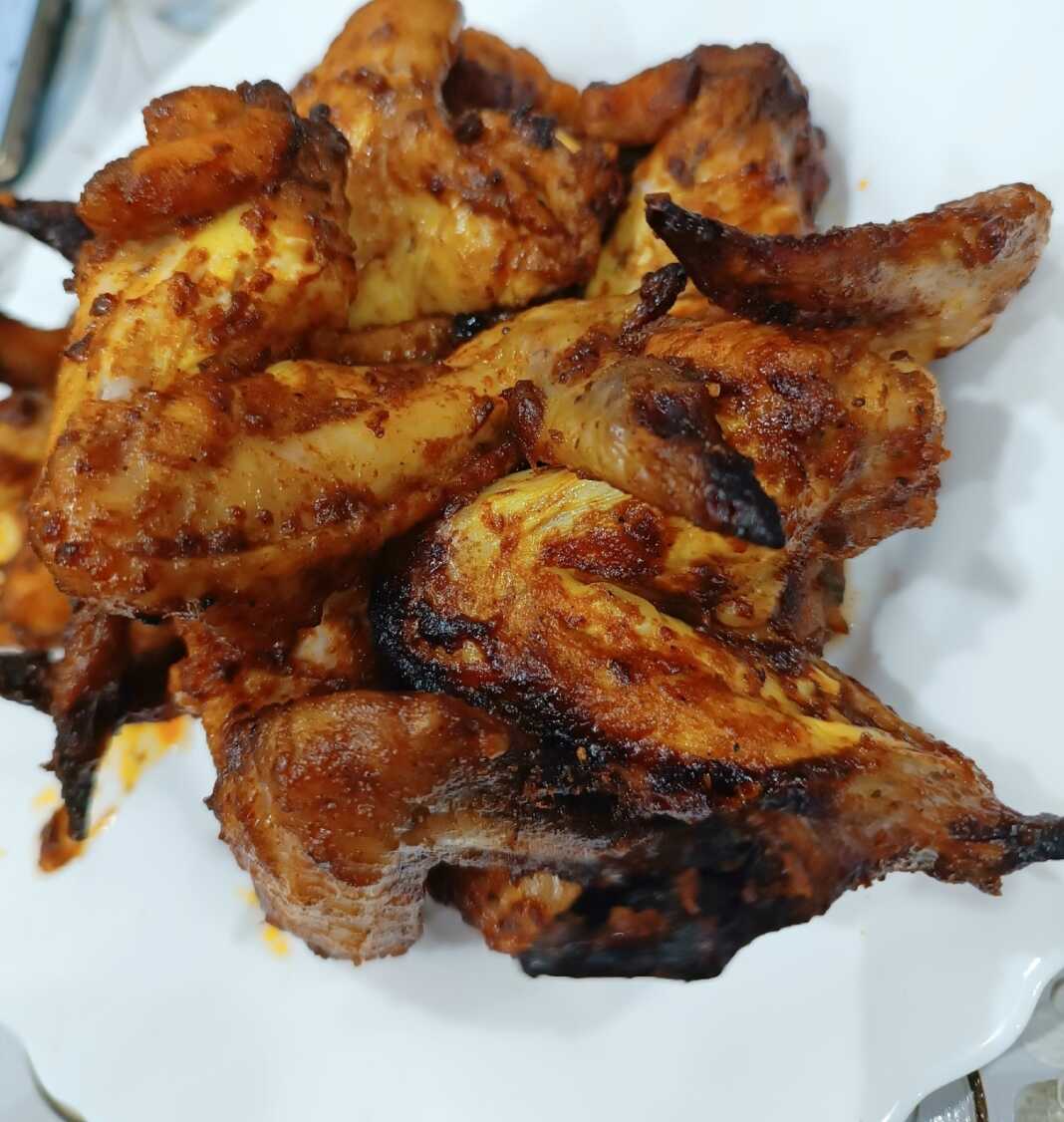 Τραγανές φτερούγες κοτόπουλο καλυμμένες με γυαλιστερή σάλτσα BBQ και συνοδευόμενες από χρυσαφένιες πατάτες country style.