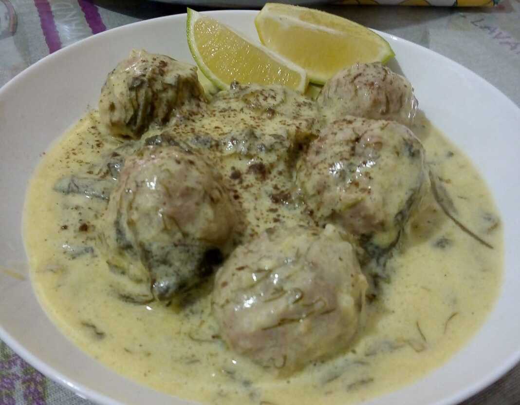 ενα βαθυ πιάτο με λευκά γιουβαρλάκια και καταπράσινα άγρια χόρτα μέσα σε μια πυκνή σάλτσα αυγολέμονο.