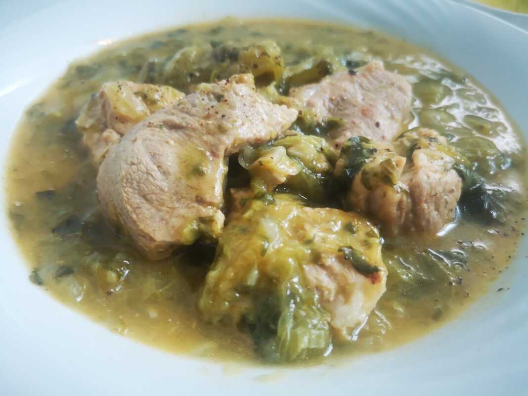 Ένα βαθύ πιάτο με τρυφερά κομμάτια χοιρινού και σέλινο, καλυμμένα με μια πλούσια, κρεμώδη σάλτσα αυγολέμονου και πασπαλισμένα με φρέσκο πιπέρι.