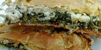 Μια χρυσαφένια και τραγανή σπανακοτυρόπιτα σε κομμάτια που φαίνονται οι στρώσεις των φύλλων και η πλούσια πράσινη γέμιση.