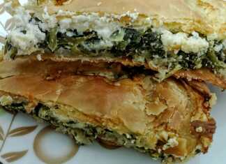 Μια χρυσαφένια και τραγανή σπανακοτυρόπιτα σε κομμάτια που φαίνονται οι στρώσεις των φύλλων και η πλούσια πράσινη γέμιση.