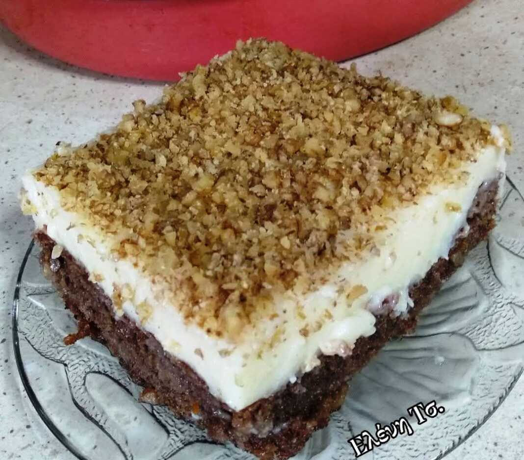 Ένα κομμάτι σιροπιαστής πουτίγκας με βάση καρυδόπιτας και μια παχιά στρώση λευκής κρέμας πατισερί πασπαλισμένο με τριμμένο καρύδι.