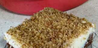 Υπέροχη Πουτίγκα με Βελούδινη Κρέμα: Μια Γευστική Πανδαισία! Ένα κομμάτι σιροπιαστής πουτίγκας με βάση καρυδόπιτας και μια παχιά στρώση λευκής κρέμας πατισερί πασπαλισμένο με τριμμένο καρύδι.