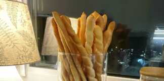 Ιταλικά Κριτσίνια: Η Τραγανή Απόλαυση που Κατέκτησε τον Κόσμο! Μια δέσμη από μακριά, χρυσαφένια και στριφτά ιταλικά κριτσίνια μέσα σε ένα γυάλινο βάζο, πασπαλισμένα με σουσάμι.