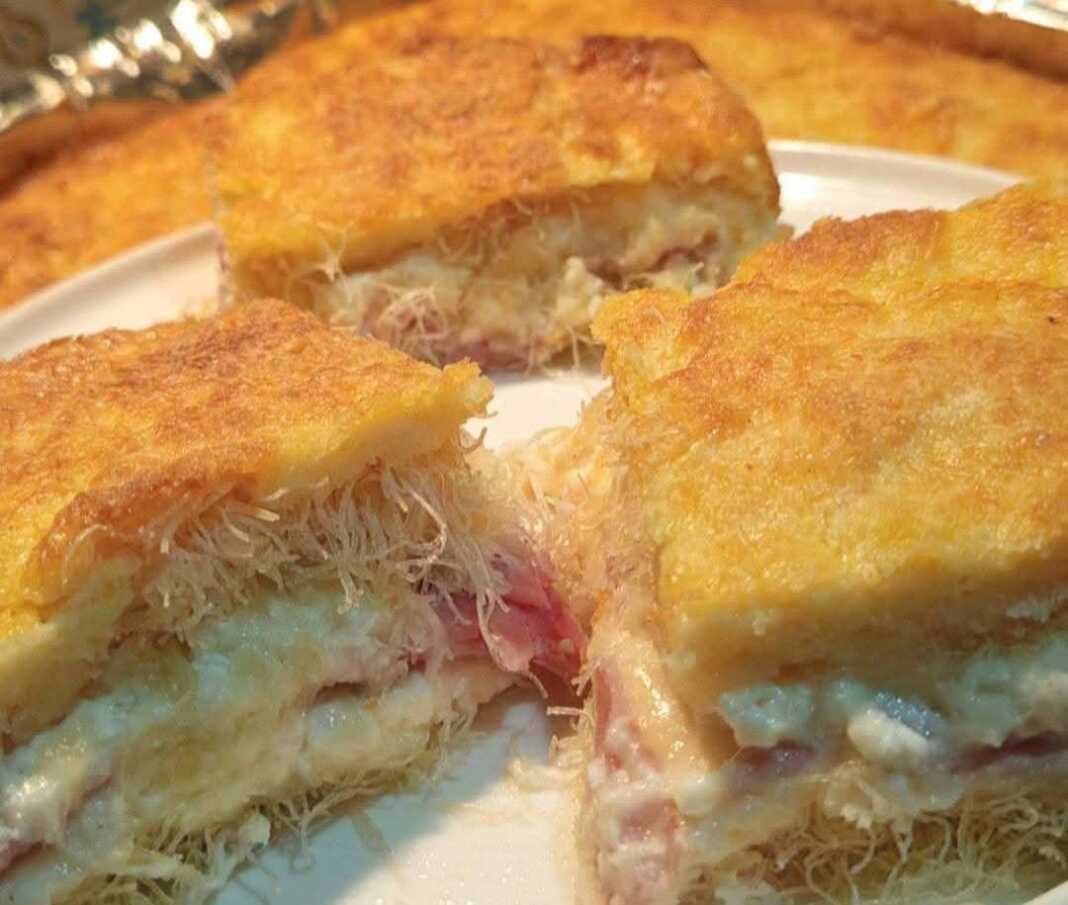 Ροδοκοκκινισμένο αλμυρό κανταΐφι, κομμένο σε τετράγωνα κομμάτια, με τα λιωμένα τυριά να φαίνονται ανάμεσα στις ίνες του φύλλου.