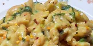 κοχυλάκια κόκκινης φακής μέσα σε κρεμώδη σάλτσα με σπανάκι και τριμμένο καρότο, διακοσμημένο με φρέσκο βασιλικό.