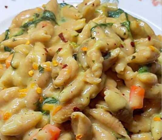 κοχυλάκια κόκκινης φακής μέσα σε κρεμώδη σάλτσα με σπανάκι και τριμμένο καρότο, διακοσμημένο με φρέσκο βασιλικό.