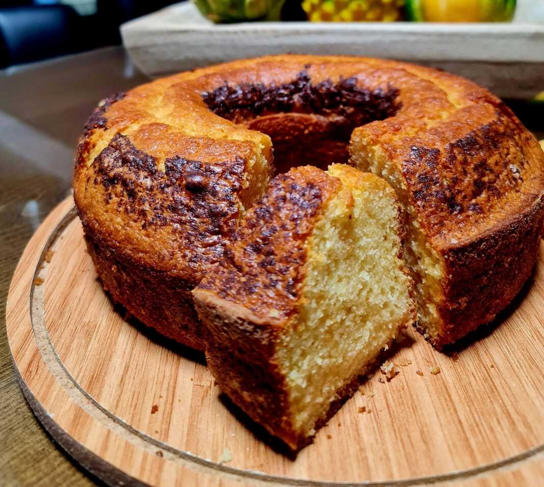 Ένα χρυσαφένιο κέικ μανταρινιού φόρμας, πασπαλισμένο με άχνη ζάχαρη και διακοσμημένο με φέτες φρέσκου μανταρινιού.