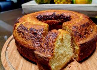 Ένα χρυσαφένιο κέικ μανταρινιού φόρμας, πασπαλισμένο με άχνη ζάχαρη και διακοσμημένο με φέτες φρέσκου μανταρινιού.