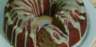 Ένα ψηλό, αφράτο κέικ γεμάτο με πολύχρωμα αποξηραμένα φρούτα και ξηρούς καρπούς, πασπαλισμένο με άχνη ζάχαρη.