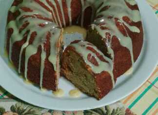 Ένα ψηλό, αφράτο κέικ γεμάτο με πολύχρωμα αποξηραμένα φρούτα και ξηρούς καρπούς, πασπαλισμένο με άχνη ζάχαρη.