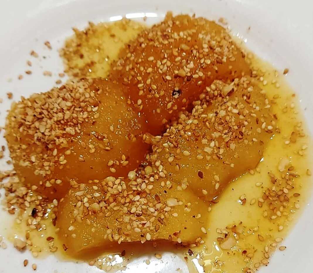 ζεστή κομπόστα μήλου, περιχυμένα με σιρόπι πορτοκαλιού και πασπαλισμένα με καρύδια και σουσάμι.