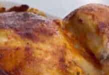 Ολόκληρο ψημένο κοτόπουλο με χρυσαφένια πέτσα περιτριγυρισμένο από μικρές πατάτες baby μέσα σε ένα ταψί.