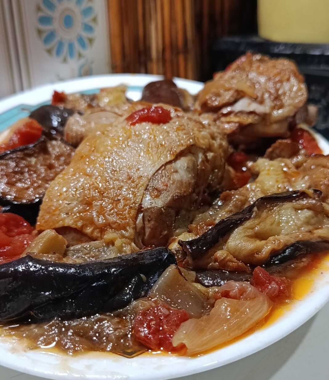 Μια βαθιά κατσαρόλα με κοκκινιστό κοτόπουλο και μελωμένες μελιτζάνες, αρωματισμένη με ξυλάκι κανέλας και δαφνόφυλλα.