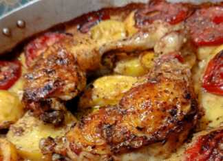 Ένα ταψί με ροδοκοκκινισμένα μπούτια κοτόπουλο, πατάτες κομμένες σε ροδέλες και ψημένες φέτες ντομάτας, περιχυμένα με σάλτσα μουστάρδας.