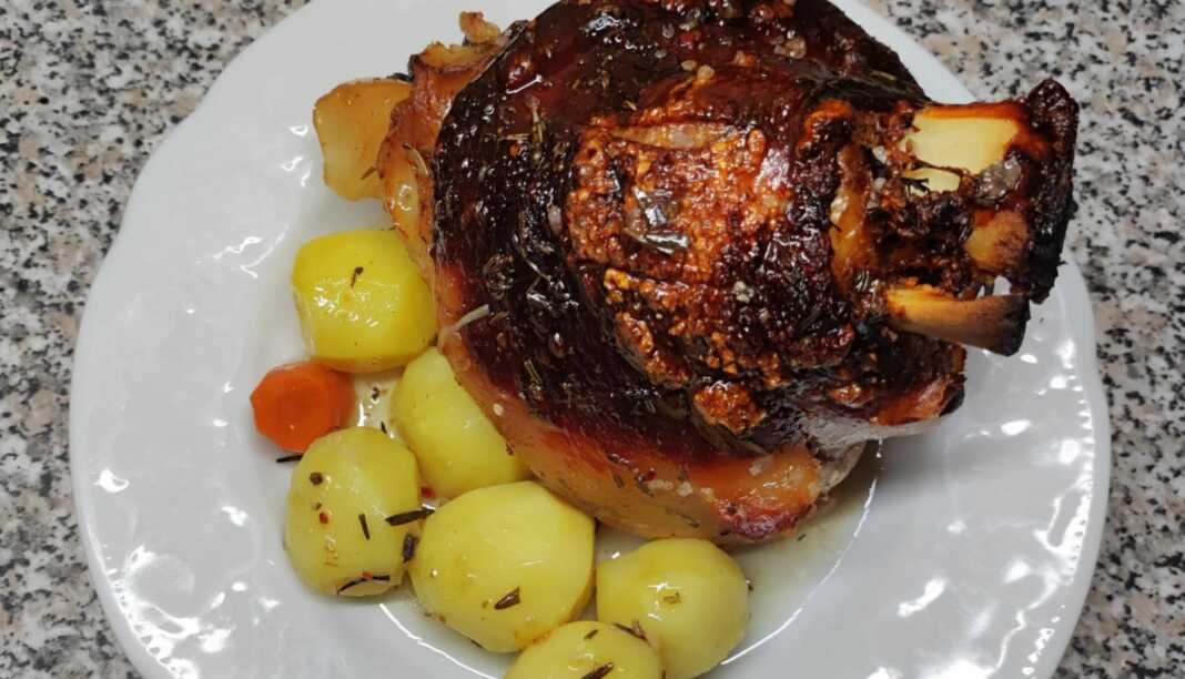 Τέσσερα ροδοκοκκινισμένα χοιρινά κότσια με τραγανή πέτσα, σερβιρισμένα με πουρέ πατάτας και σάλτσα.