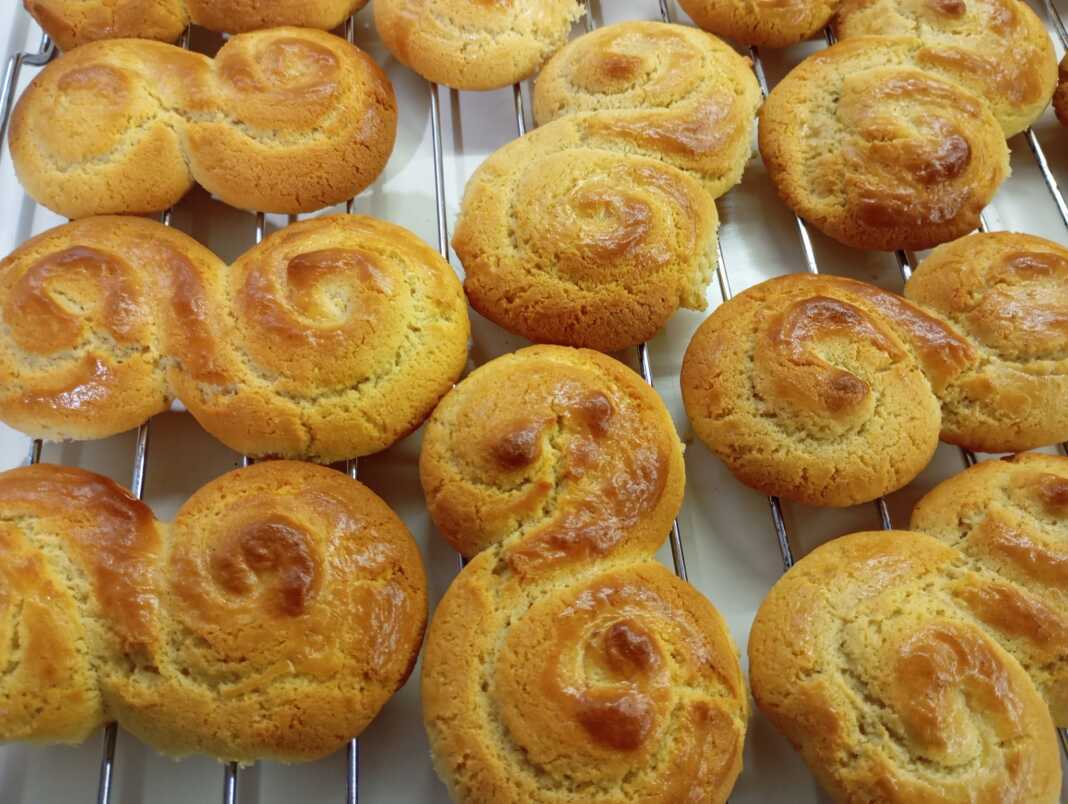 Ένα μεγάλο καλάθι γεμάτο με διάφορα σχέδια από παραδοσιακά πασχαλινά κουλουράκια, γυαλιστερά από το αυγό και καλοψημένα.