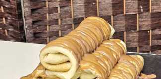 Μια στοίβα από λεπτές, χρυσαφένιες κρέπες σε ένα πιάτο, γαρνιρισμένες με ρευστή πραλίνα φουντουκιού και τριμμένο μπισκότο.