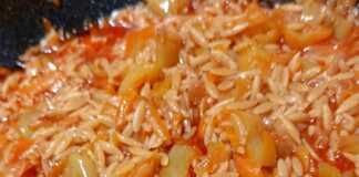 Ένα πιάτο μελωμένο κριθαράκι, κόκκινες και πράσινες πιπεριές, τριμμένο καρότο και πλούσια κόκκινη σάλτσα.