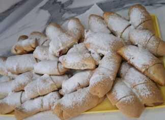 Ένας δίσκος με χρυσαφένια κρουασανάκια πασπαλισμένα με άχνη ζάχαρη, δίπλα σε ένα μπολάκι με μαρμελάδα μήλο.