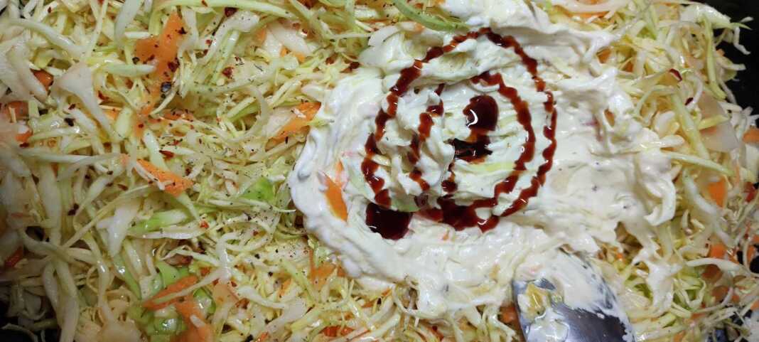 Ένα μπολ με πλούσια λαχανοσαλάτα, στολισμένη με τρίμμα καρότου και ξινόμηλου, σε ένα φωτεινό τραπέζι.