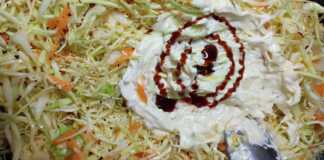 Ένα μπολ με πλούσια λαχανοσαλάτα, στολισμένη με τρίμμα καρότου και ξινόμηλου, σε ένα φωτεινό τραπέζι.