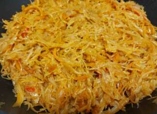 Μια βαθιά κατσαρόλα με αχνιστό λάχανο γιαχνί, κομμάτια κοτόπουλου και πλούσια κόκκινη σάλτσα, γαρνιρισμένη με δάφνη.