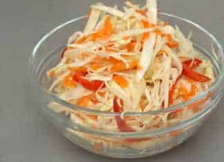 Ένα γυάλινο μπολ γεμάτο με ψιλοκομμένο λάχανο, καρότο και πιπεριές σε μαρινάδα, δίπλα σε ένα μπολ με την ίδια δροσερή σαλάτα.