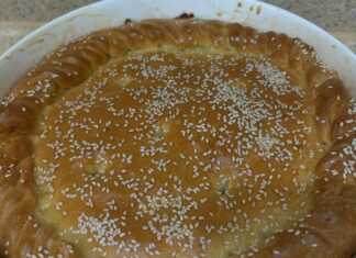 Μια χρυσαφένια, στρογγυλή πίτα με λάχανο πασπαλισμένη με σουσάμι, κομμένη σε τριγωνικά κομμάτια που φαίνονται αφράτα.